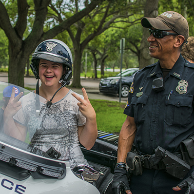 Participant sitting on a police officers motorcycle laughing.